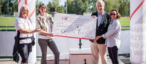 Drei Frauen und ein Mann halten gemeinsam einen großen Spendenscheck
