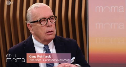 Mann mit weißen Haaren und Brille im TV-Studio.