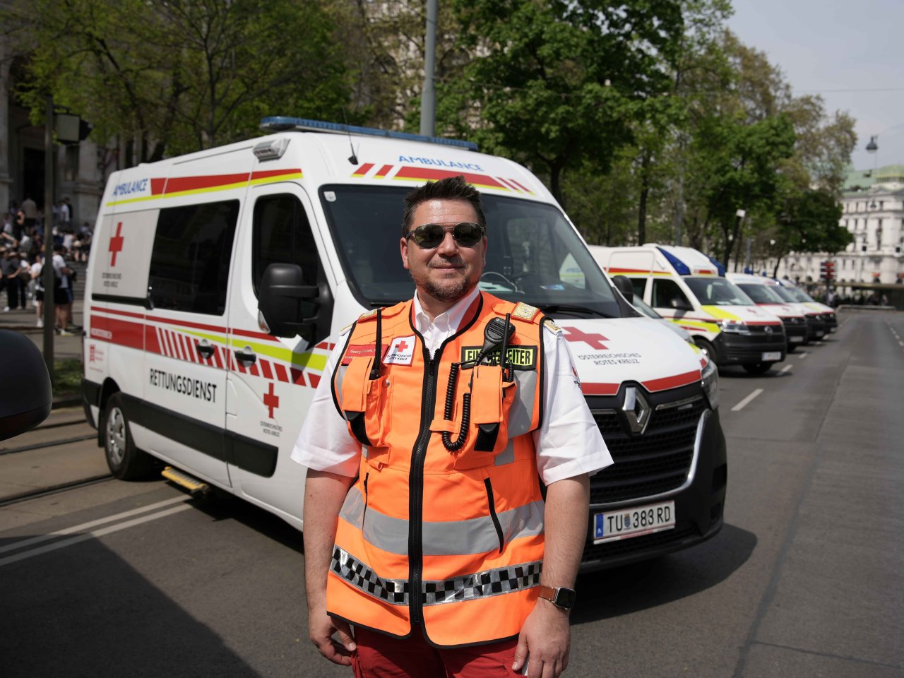 Der Einsatzleiter steht vor Fahrzeugen des Roten Kreuzes.