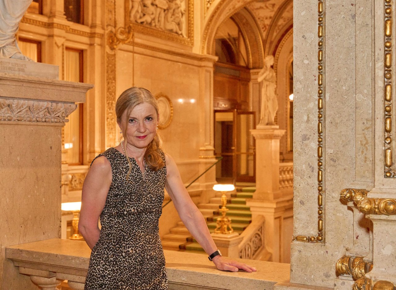 Die Betriebsärztin steht im Stiegenhaus der Staatsoper und blickt in die Kamera.