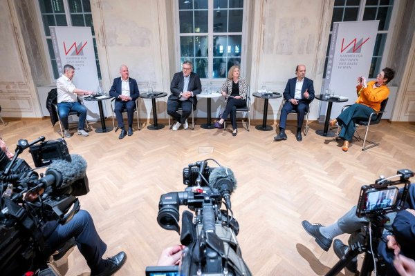 Diskussionsrunde mit sechs Personen am Podium, auf die TV-Kameras gerichtet sind.