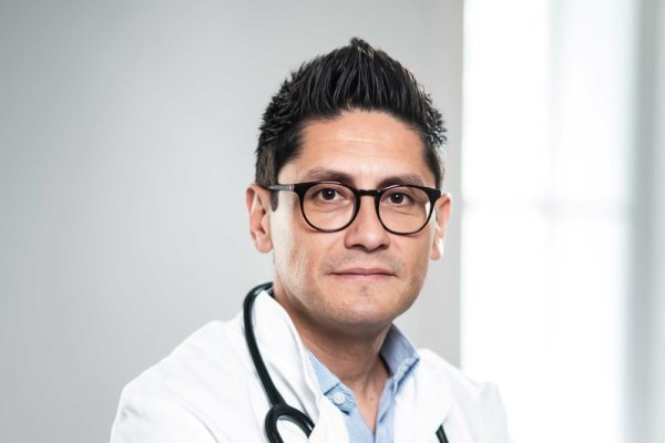 Mann im weißen Arztkittel mit verschränkten Armen.