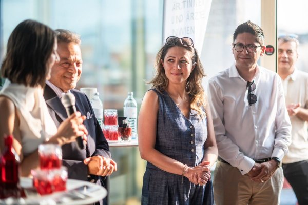 Gruppe von fünf Personen - zwei Frauen und drei Männern - bei der Eröffnung des Festes, mit Bildfokus auf eine Frau im Sommerkleid.