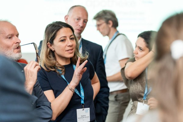 Fünf Personen im Gespräch, im Bildfokus eine Frau. 