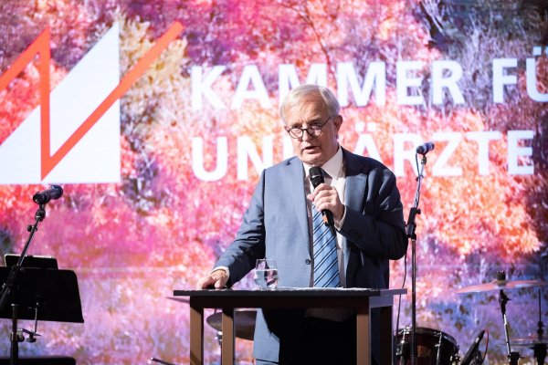 Mann auf einer Bühne mit Pult stehend.