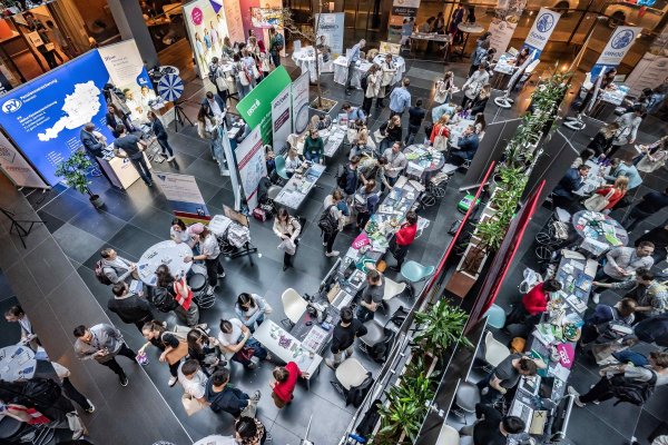 Blick in die Messe-Halle, mit zahlreichen Menschen an Messeständen.