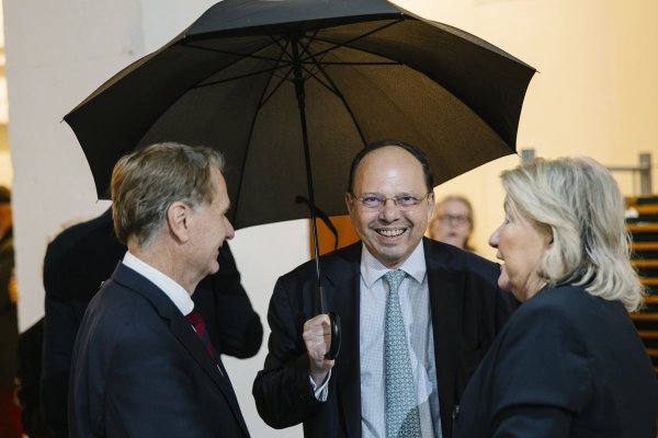 Mann mit Schirm und neben zwei weiteren Personen.