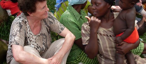 Frau Hengstberger sitzt auf einer Wiese am Boden mit einer anderen Frau, die ein Baby bei sich hat