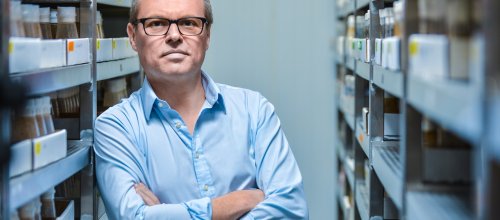 Gero Miesenböck, Neurophysiologe, lehnt sich an einem offenen Kasten-Ablage-System an, mit verschränkten Händen