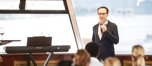 Der Funktionär Philipp Ubl steht mit einem Mikrofon in der Hand und hält einen Vortrag vor mehreren Personen.