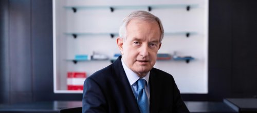 Mann mit Hemd, Krawatte und Sakko sitzt im Büro am Schreibtisch.