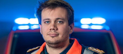 Zu sehen ist der Einsatzleiter der Wiener Berufsrettung, Dominik Kalmar, der eine typische Rettungsjacke trägt - hinter ihm ist ein Rettungswagen zu sehen.