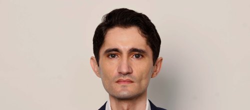 Der Journalist Köksal Baltaci von "Die Presse" blickt direkt in die Kamera. Der Hintergrund ist hell und einfärbig. 