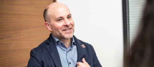 Der Arzt, Funktionär und Vorsitzender des Verwaltungsausschusses des Wohlfahrtsfonds Michael Lazansky sitzt bei einem Gespräch und lächelt, während er die linke Hand am Revers des Sakko hält. 