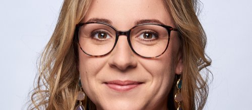 Frau mit Brille lächelt in die Kamera.