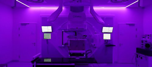Ein Foto von einer Radioonkologie-Strahlenanlage - der Raum ist in violettes Licht getaucht.