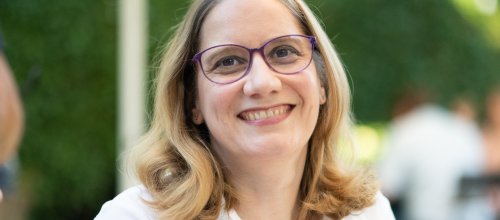 Frau mit Brille lächelt in die Kamera.