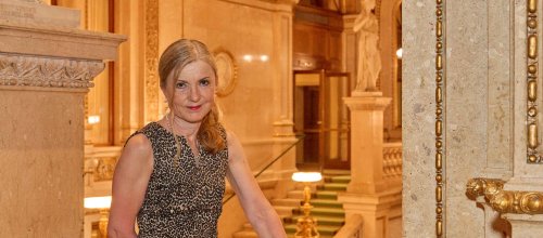 Eine Frau steht im Stiegenhaus der Wiener Staatsoper.