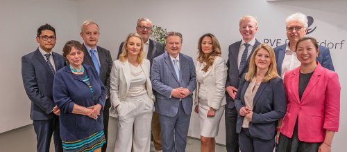 Elf Personen stehen im Rahmen einer feierlichen Eröffnung einer Primärversorgungseinheit beisammen.