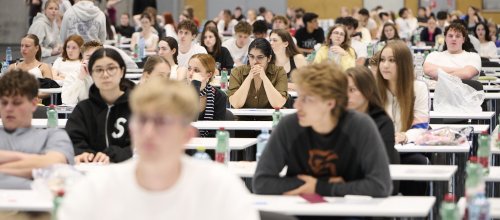Junge Menschen an Bänken in einem großen Saal