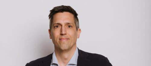 Der Geschäftsführer von neunerhaus Gesundheit sieht entschlossen in die Kamera. Er trägt ein helles Hemd und ein dunkles Sakko.