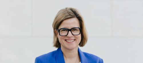 Frau in Jacke und Brille schaut frontal in die Kamera