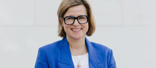Frau in Jacke und Brille schaut frontal in die Kamera