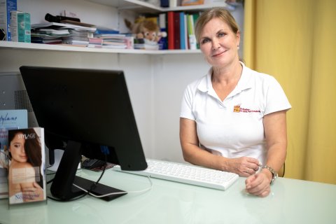 Frau Dr. Sylvia Perl-Convalexius sitzt in ihrer Ordination am Schreibtisch