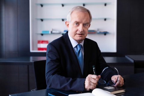 Mann mit Hemd, Krawatte und Sakko sitzt im Büro am Schreibtisch.