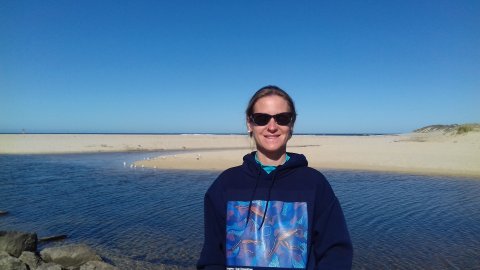 Frau mit Sonnenbrille steht an einem Fluss.