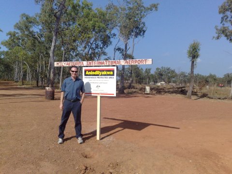 Ein Mann mit Sonnenbrille steht neben einem Straßenschild.
