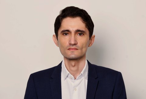 Der Journalist Köksal Baltaci von "Die Presse" blickt direkt in die Kamera. Der Hintergrund ist hell und einfärbig. 