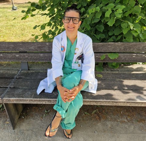 Mariam Vedadinejad in spitalsärztlicher Berufskleidung, auf einer Parkbank sitzend.