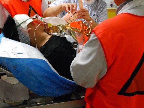 Man sieht einen Mann auf einer Bahre, der notärztlich versorgt wird.