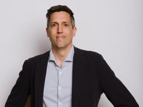 Der Geschäftsführer von neunerhaus Gesundheit sieht entschlossen in die Kamera. Er trägt ein helles Hemd und ein dunkles Sakko.