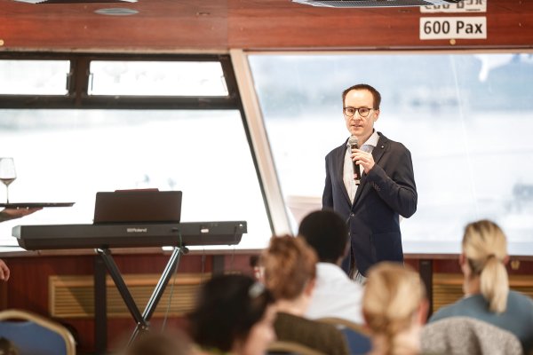 Der Funktionär Philipp Ubl steht mit einem Mikrofon in der Hand und hält einen Vortrag vor mehreren Personen.
