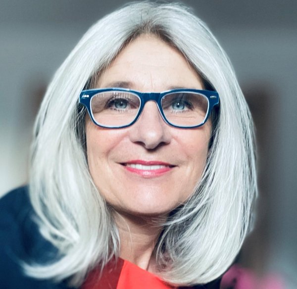 Frau mit Brille lächelt in die Kamera. 