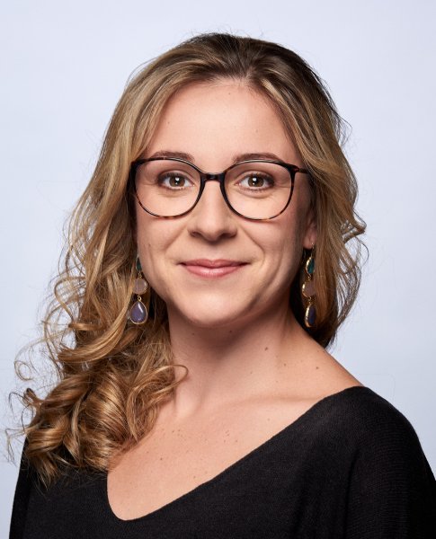 Frau mit Brille lächelt in die Kamera.